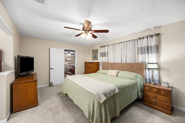 bedroom featuring light carpet, ceiling fan, baseboards, and a textured ceiling