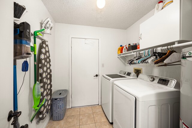 laundry room featuring light tile patterned floors, laundry area, a textured ceiling, and washing machine and clothes dryer