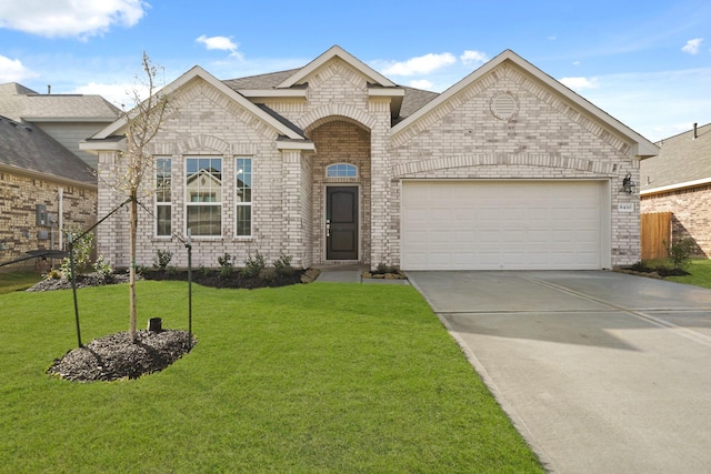 french country home featuring a front yard, concrete driveway, brick siding, and a garage