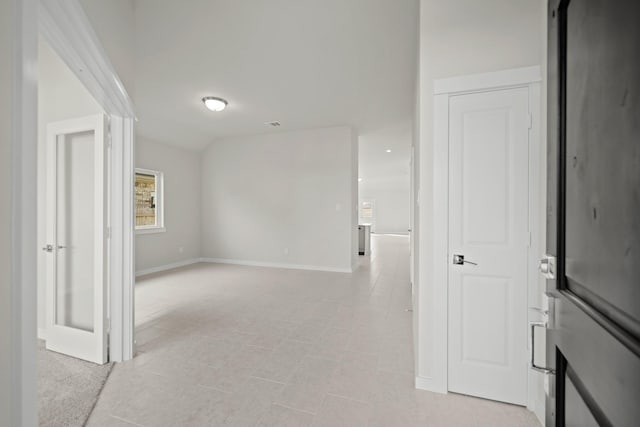 hallway featuring baseboards and vaulted ceiling