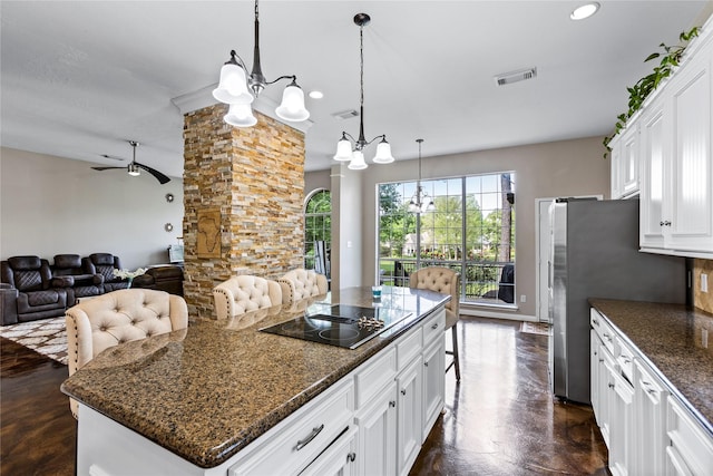 kitchen featuring visible vents, a center island, a kitchen bar, white cabinetry, and pendant lighting