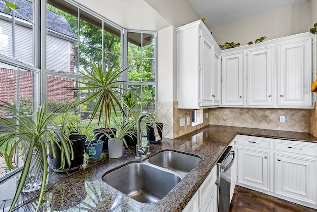 kitchen with dark stone countertops, decorative backsplash, white cabinets, and a sink