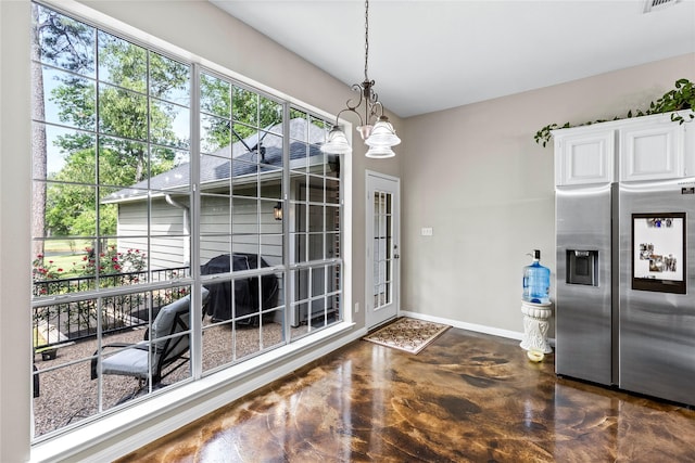 entryway featuring finished concrete floors, a chandelier, visible vents, and baseboards