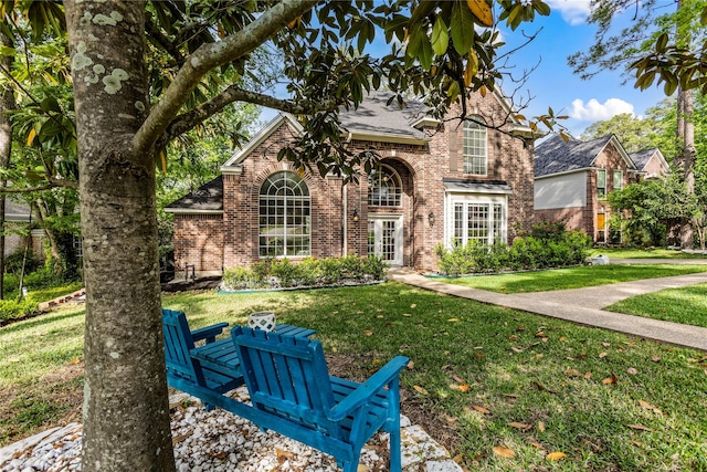 traditional home with brick siding, a front lawn, and roof with shingles