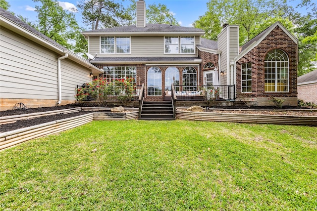 rear view of property featuring a chimney, a lawn, and brick siding