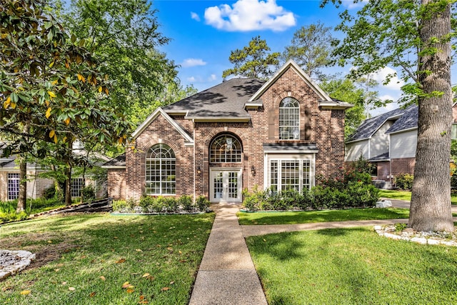 traditional-style home with french doors, brick siding, and a front lawn