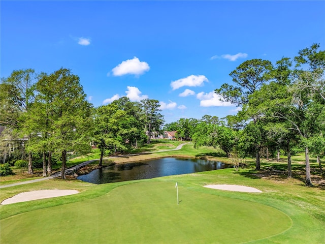 view of community with view of golf course, a water view, and a lawn