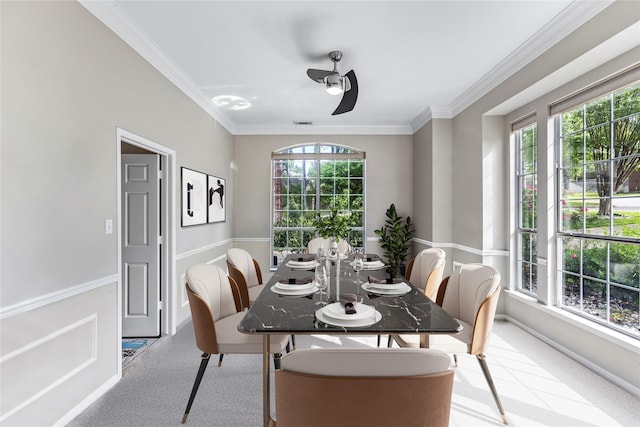 carpeted dining room with plenty of natural light, ornamental molding, and ceiling fan