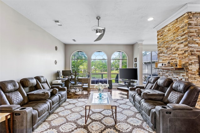 living room featuring a textured ceiling, visible vents, and ornate columns