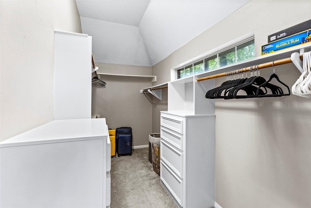 walk in closet featuring lofted ceiling and light colored carpet