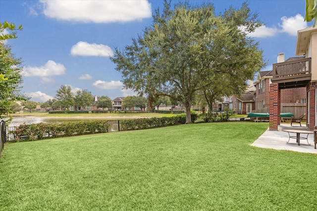 view of yard with a trampoline, a water view, a patio, and fence