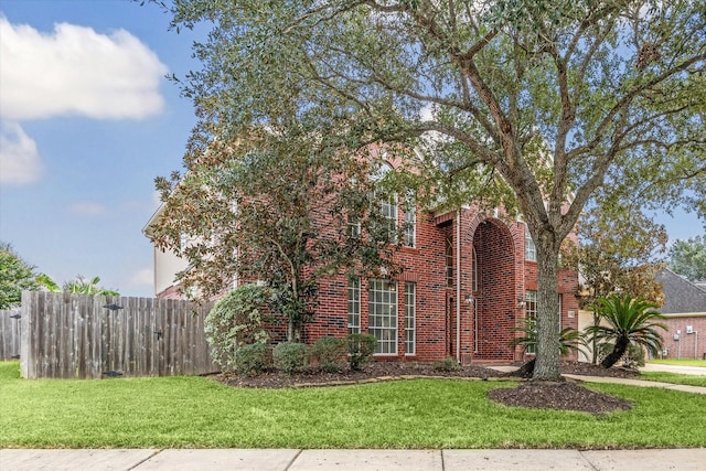 view of front of property with brick siding, fence, and a front lawn