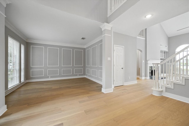 interior space featuring light wood-type flooring, a decorative wall, ornate columns, and stairs