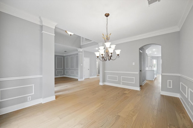 spare room with arched walkways, visible vents, light wood-style flooring, a decorative wall, and a notable chandelier