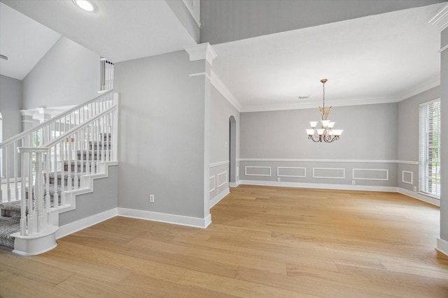 empty room with arched walkways, baseboards, light wood-style flooring, stairway, and an inviting chandelier