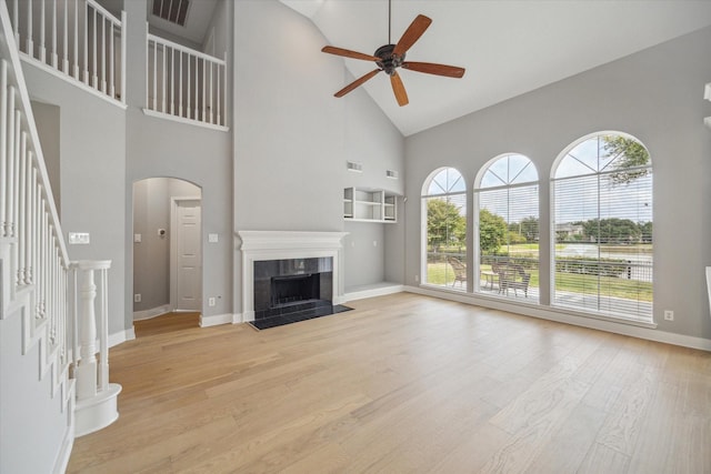 unfurnished living room featuring light wood finished floors, visible vents, a tiled fireplace, ceiling fan, and stairway