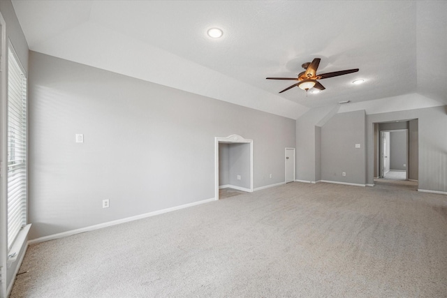 carpeted empty room featuring vaulted ceiling, baseboards, and ceiling fan