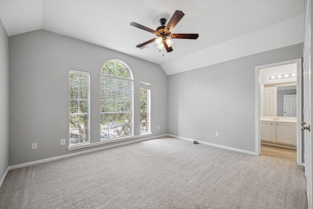 empty room featuring a ceiling fan, lofted ceiling, light colored carpet, and baseboards