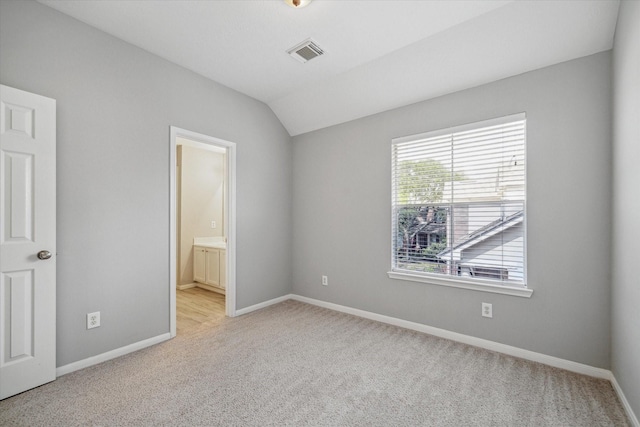 unfurnished bedroom featuring lofted ceiling, visible vents, light carpet, and baseboards