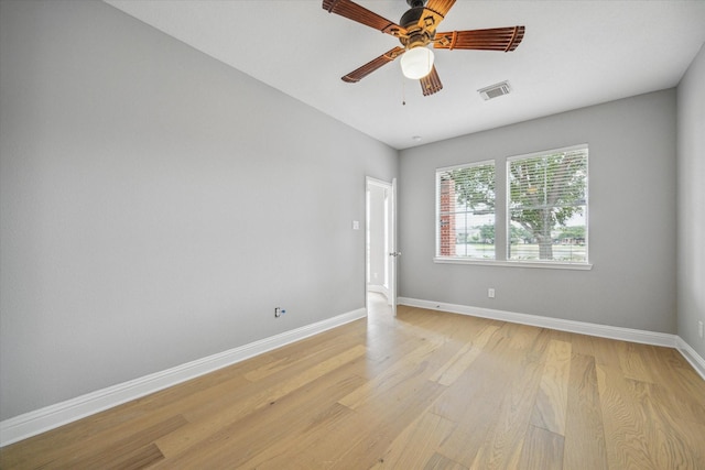 spare room featuring a ceiling fan, light wood-style flooring, visible vents, and baseboards