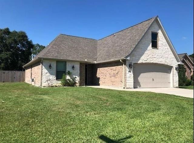 view of front of property featuring concrete driveway, fence, and a front lawn