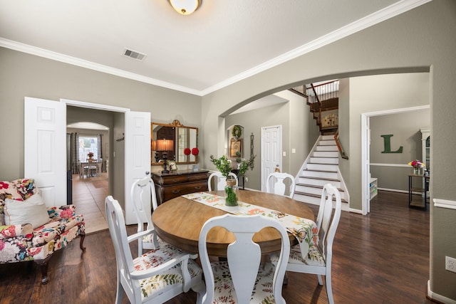 dining area featuring arched walkways, dark wood-style flooring, visible vents, and stairway