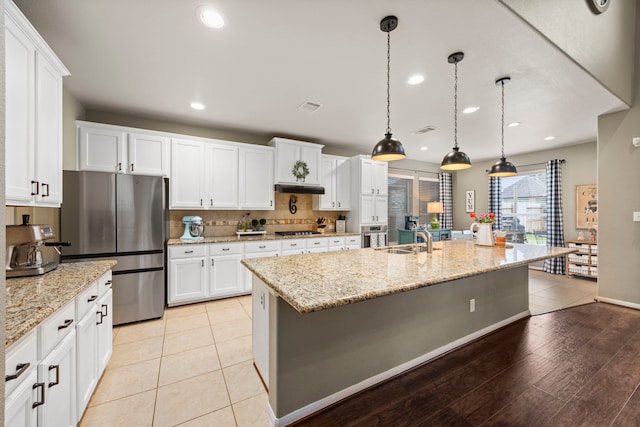 kitchen featuring hanging light fixtures, a center island with sink, white cabinetry, and stainless steel appliances