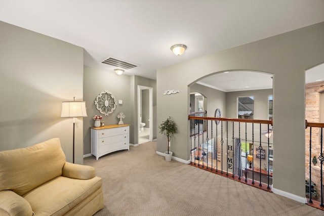 sitting room with light carpet, baseboards, visible vents, and arched walkways