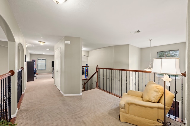 corridor with light carpet, baseboards, visible vents, and an upstairs landing