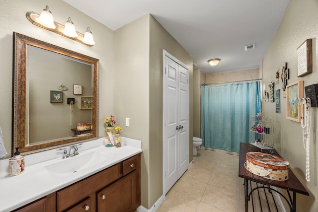 bathroom with visible vents, toilet, tile patterned floors, vanity, and a closet