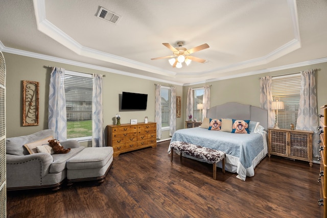 bedroom with a raised ceiling, visible vents, and multiple windows