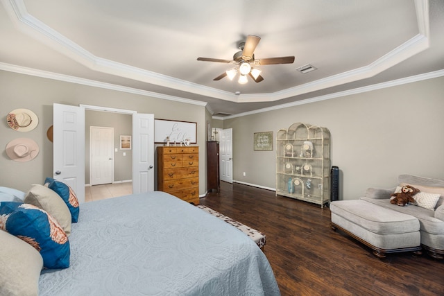 bedroom with a tray ceiling, visible vents, ceiling fan, and wood finished floors