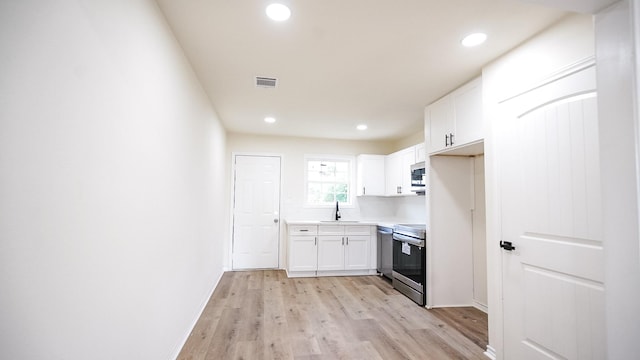 kitchen featuring visible vents, white cabinets, appliances with stainless steel finishes, light countertops, and a sink