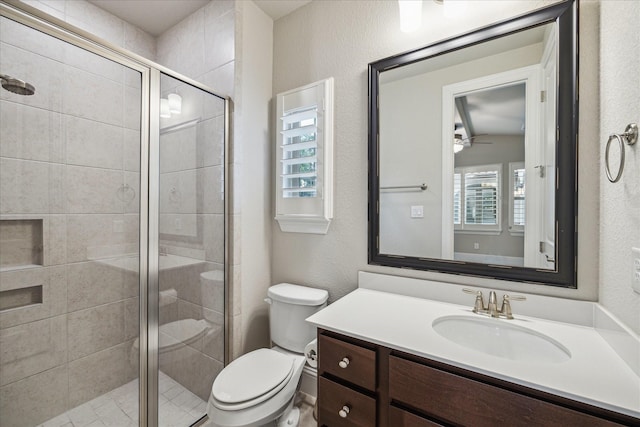 bathroom featuring a stall shower, a textured wall, vanity, and toilet