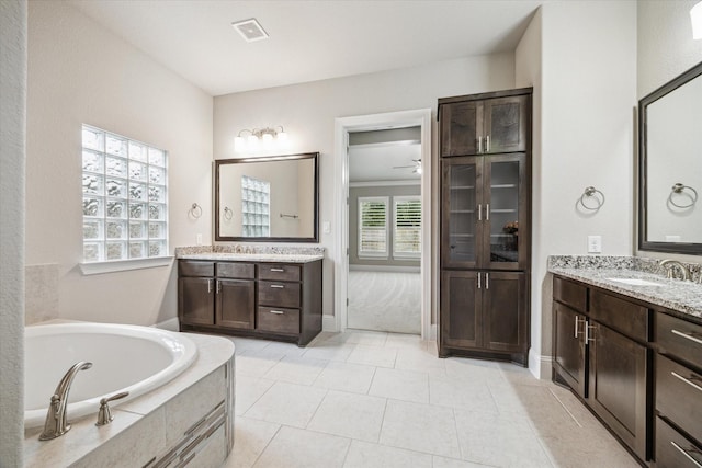 full bath with tile patterned flooring, two vanities, a sink, visible vents, and a bath