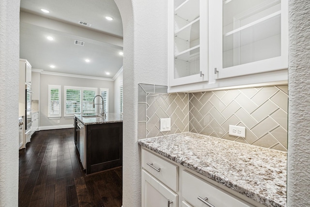 kitchen featuring glass insert cabinets, visible vents, white cabinetry, and a sink