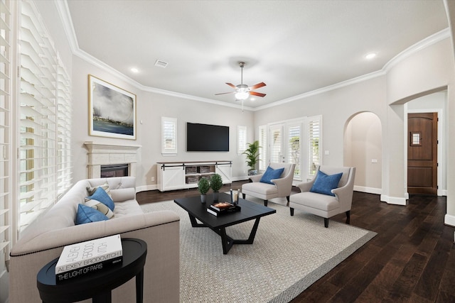 living room with arched walkways, dark wood-type flooring, a glass covered fireplace, and baseboards