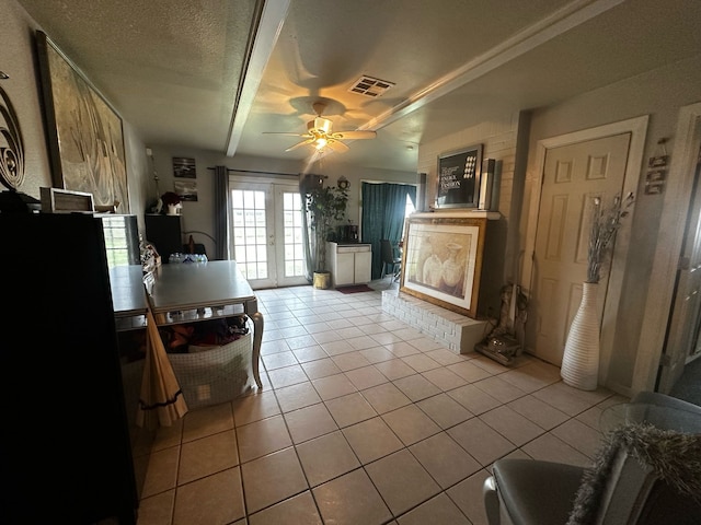 interior space with french doors, light tile patterned floors, visible vents, ceiling fan, and a textured ceiling