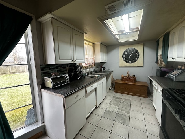 kitchen featuring dark countertops, a sink, visible vents, and white cabinetry