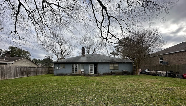 back of house with a yard, a chimney, and fence