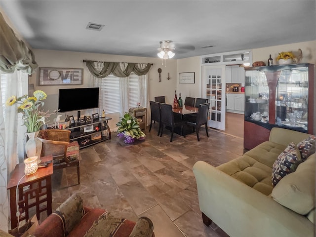 living area with french doors, visible vents, and ceiling fan