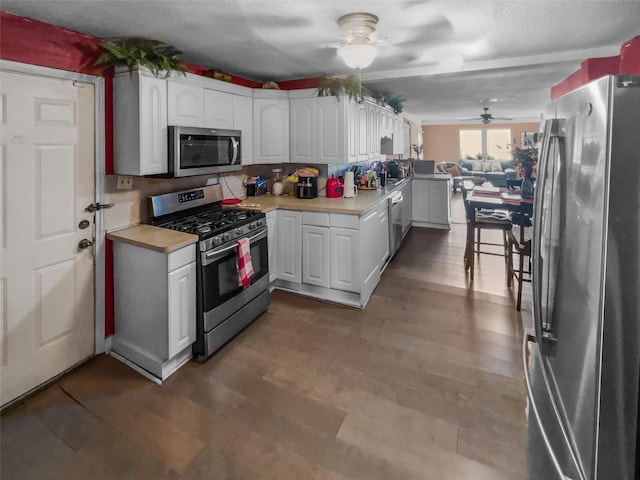 kitchen featuring stainless steel appliances, white cabinets, light countertops, and wood finished floors