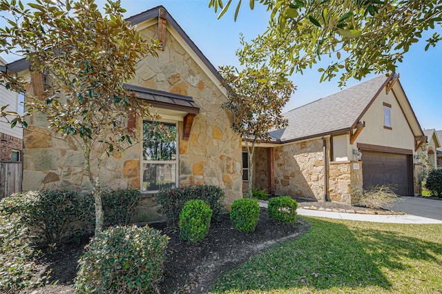 view of front of house with stone siding, roof with shingles, concrete driveway, a front yard, and an attached garage