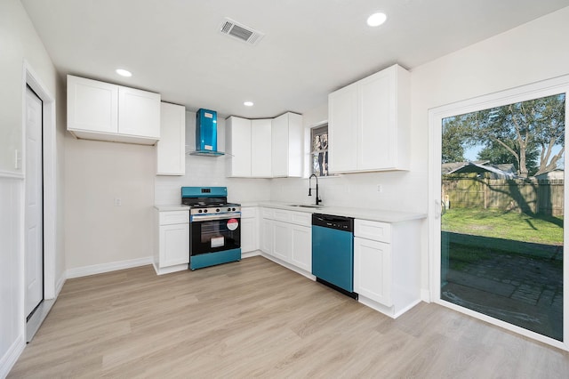 kitchen with light wood-style floors, a sink, wall chimney range hood, stainless steel gas range, and dishwasher