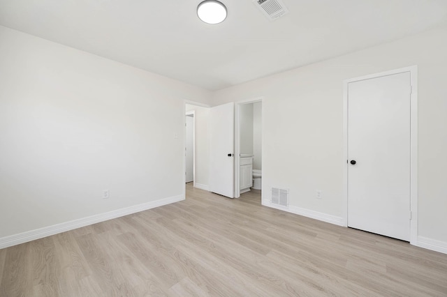 unfurnished bedroom featuring light wood-style floors, visible vents, ensuite bath, and baseboards