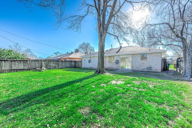 back of property with brick siding, a lawn, and a fenced backyard