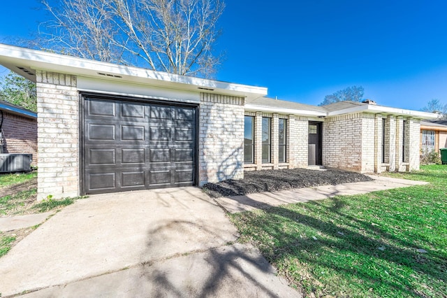 view of front of house with brick siding, concrete driveway, a front yard, a garage, and cooling unit