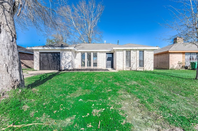 rear view of property featuring driveway, brick siding, a lawn, and an attached garage