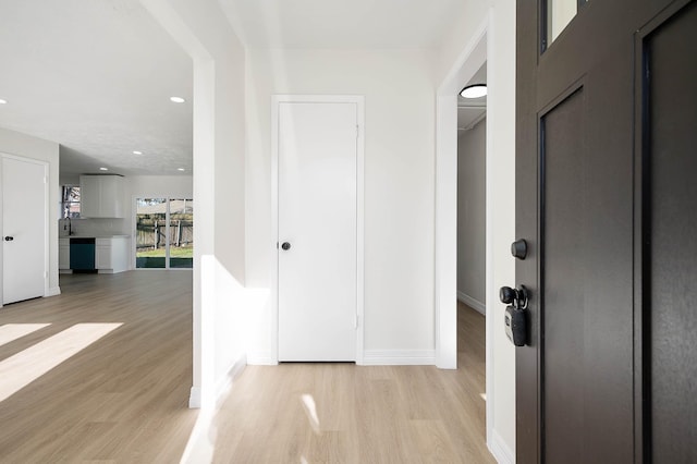 corridor featuring light wood finished floors, baseboards, and recessed lighting