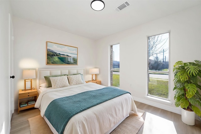 bedroom with light wood-type flooring, visible vents, and baseboards